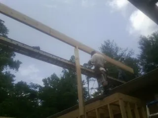 Carpenter setting a ridge beam over a new addition frame — Ice Dam Removal by Roofing Brothers in Shannock