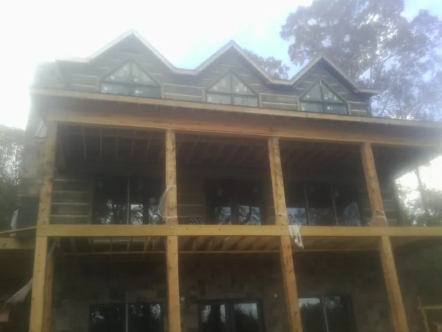 Dormers and porch framing on a large log home under construction — Roof Coating work by our crew in Shannock