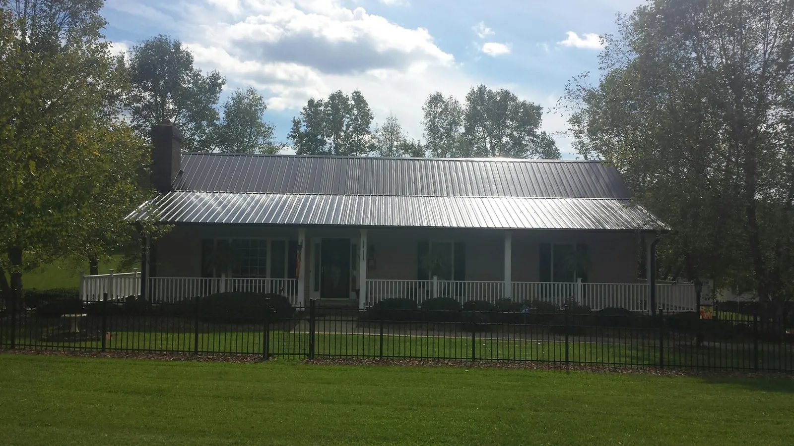 Gray metal roof on a brick ranch with a full width front porch — Gutter Guard Installation work by our crew in Shannock