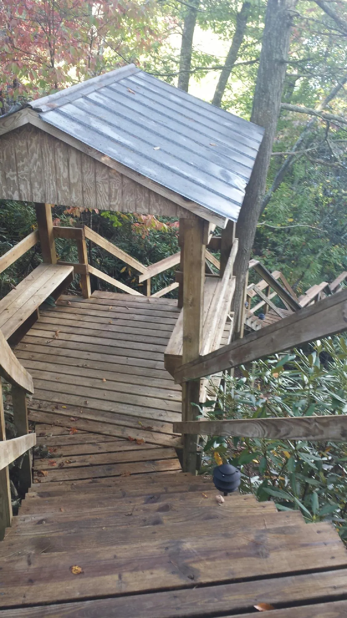Metal roofed shelter over wooden steps on a wooded walkway — Skylight Repair & Installation work by our crew in Shannock