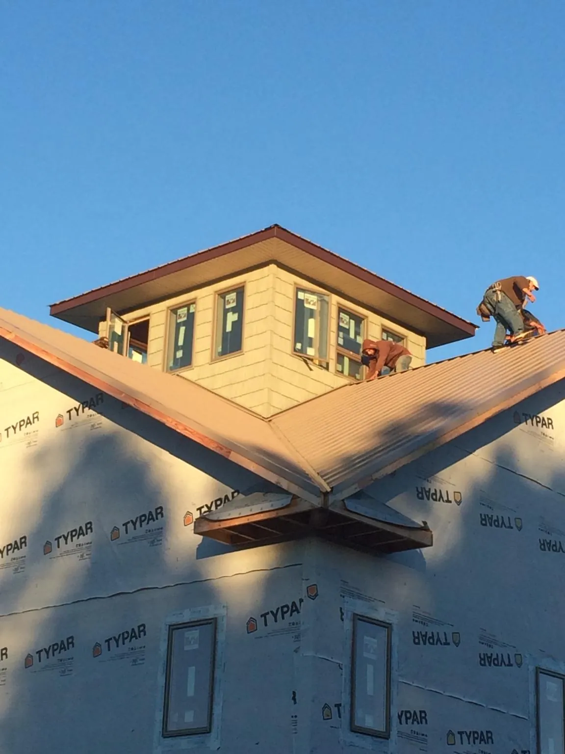 Roofers working around a rooftop cupola on a new metal roof at sunset — Roof Waterproofing in Shannock by Roofing Brothers